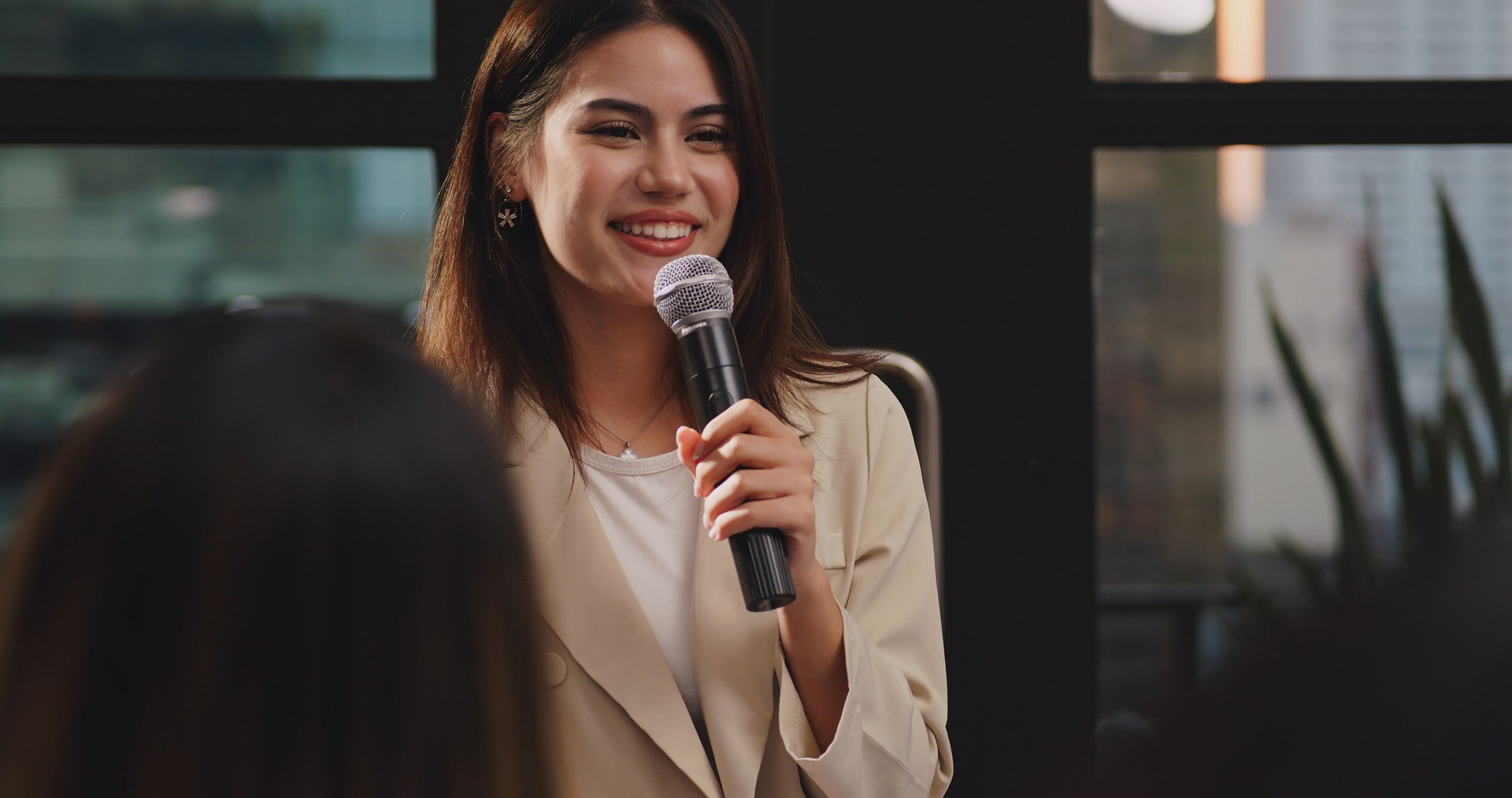 Confident young businesswoman or speaker sharing ideas with colleagues or audience during company seminar.